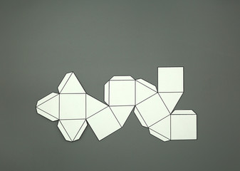 Geometric shape cut out of paper and photographed from above on grey background. Geometry net of Cuboctahedron.