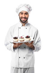 Male confectioner with tasty dessert on white background