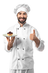 Male confectioner with tasty dessert showing thumb-up on white background