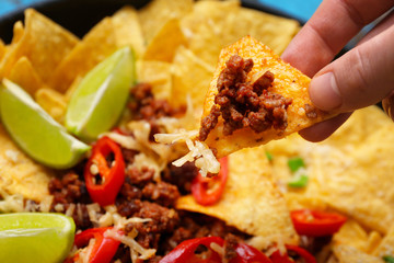 Woman eating tasty nachos with minced meat, closeup