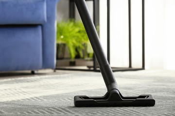 Brush of vacuum cleaner on carpet in room