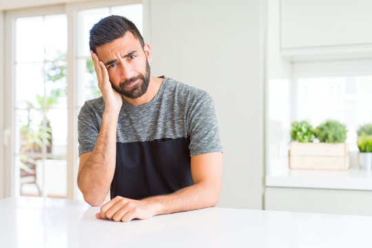 Handsome hispanic man wearing casual t-shirt at home thinking looking tired and bored with depression problems with crossed arms.
