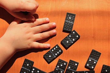 Teaching children to play dominoes game on a wooden background