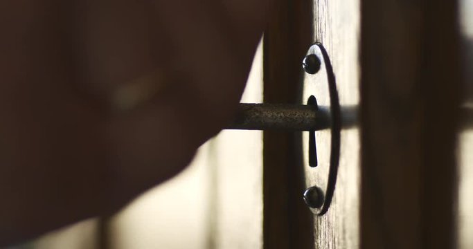 Side wiev of person by hand turns old key in the keyhole of antique wooden cabinet