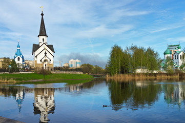 Fototapeta na wymiar St. Petersburg. Three beautiful little churches: in the name of St. George the Victorious, the Nativity of Christ, and in the name of St. Sergius of Radonezh on the bank of the pond in Pulkovo Park