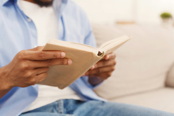 Black male student reading book at home