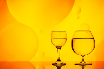 clear glass with water and oily drops on bright background