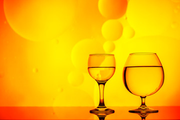 clear glass with water and oily drops on bright background