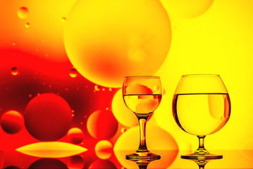 clear glass with water and oily drops on bright background