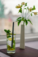 Mojito cocktail vertical shot, with the vase of flowers on the background