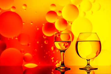 clear glass with water and oily drops on bright background