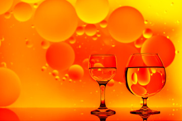 clear glass with water and oily drops on bright background