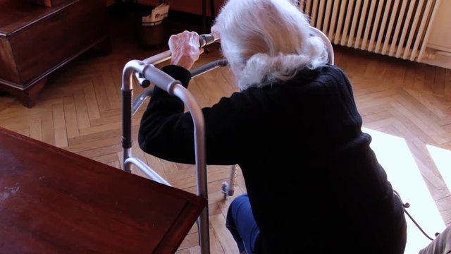 an old woman uses a walker because she has mobility problems