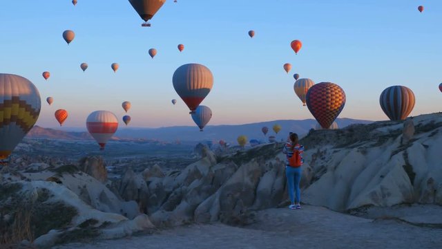 Yoing traveler with backpack looking to the air baloons. sporty girl and a lot of hot air balloons. The feeling of complete freedom, achievement, achievement, happiness