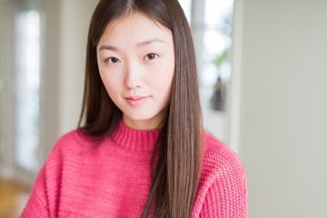 Beautiful Asian woman wearing pink sweater Relaxed with serious expression on face. Simple and natural with crossed arms