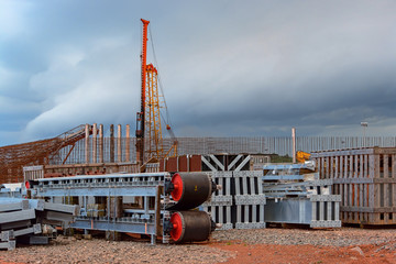 Mining equipment spare parts are stored in an open-air area in front of a warehouse under...
