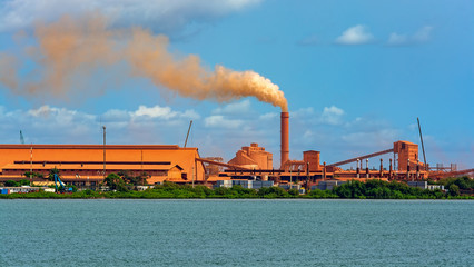 A chimney emits smoke at a bauxite industrial complex on the coast at Guinea, West Africa.