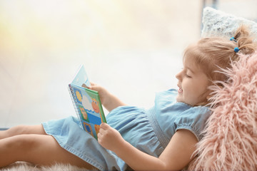 Cute little girl with book at home