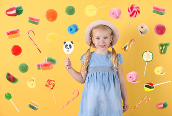 Obraz na płótnie Canvas Cute little girl with candy on color background