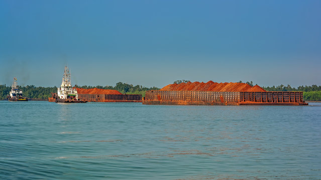 Tug boats with a large cargo barges transporting bauxite ore in Kamsar, Guinea.