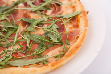 Close up of Pizza with prosciutto (parma ham) and  arugula (salad rocket)