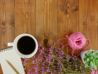 Flat lay,top view brown wooden desk with stationery including notebook and pencil with a cup of coffee,flowers and copy space