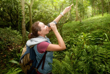 Naklejka na ściany i meble Happy woman watcher with binoculars looks wild birds in rainforest.