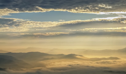 Mountain view morning of the hills around with sea of mist and soft yellow sun light in the sky background, sunrise at Doi Samur Dao, Sri Nan National Park, Nan, Thailand.