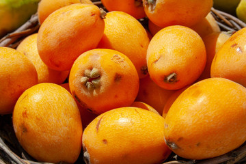 Sweet spring summer fruit, fresh loquat in a basket, close up lighted by sun