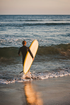 Young surfer with his white and yellow surfboard about to catch some waves