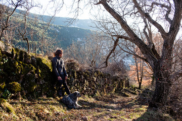 Woman with her dog in the forest enjoying sunset time.