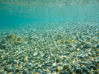 Crystal clear water and a beautiful mosaic of white shiny pebbles scattered off the seabed of the Ithaca island coast, Molos Gulf, Ionian Sea, Greece.