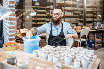 Worker painting clay jugs at the pottery shop