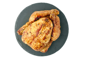 Roasted crispy chicken on round slate dish over white background
