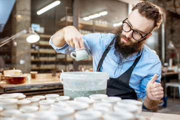 Worker painting clay jugs at the pottery shop
