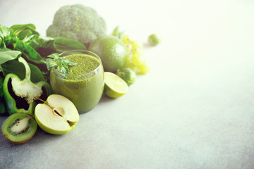 Glass with green health smoothie, kale leaves, lime, apple, kiwi, grapes, banana, avocado, lettuce. Copy space. Raw, vegan, vegetarian, alkaline food concept.