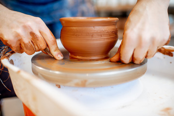Woman taking clay jug from the pottery wheel, close-up view