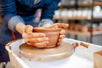 Woman taking clay jug from the pottery wheel, close-up view