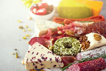 Traditional italian antipasto, cutting board with salami, cold smoked meat, prosciutto, ham, cheeses, olives, capers on grey background. Cheese and meat appetizer.