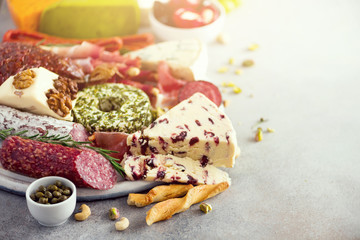 Traditional italian antipasto, cutting board with salami, cold smoked meat, prosciutto, ham, cheeses, olives, capers on grey background. Cheese and meat appetizer.