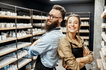 Portrait of young man and woman as a workers or business owners in the pottery shop
