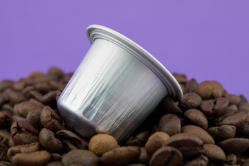 Espresso coffee capsule or coffee pod on coffee beans, purple background. Capsules.