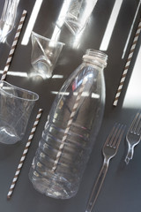 Used plastic bottles, glasses, cutlery and bags for recycling, the concept of recycling waste, ecology, land pollution on a gray background