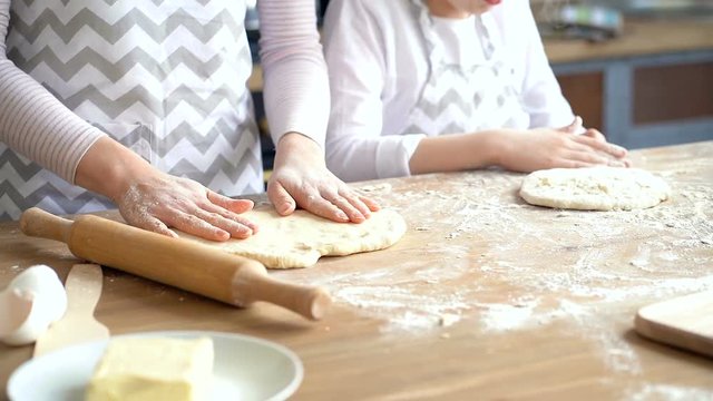 Close up. Hands of mother and little daughter p[reparing dough. Focus on the dough.