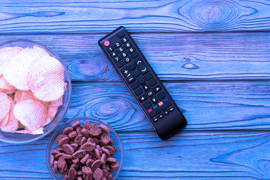 TV remote, chips, crackers on a wooden background. fans, fans, watching TV