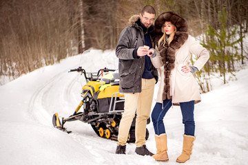 The couple rode a snowmobile. Winter fun. A married couple paves the route for travel. Navigation in the phone. A man and a woman on a snowmobile.