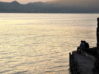 Varenna, Italy  March 30 2019 A romantic couple sits to contemplate the sunset at Lake Como