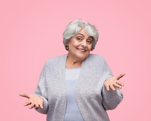 Smiling senior lady shrugging shoulders