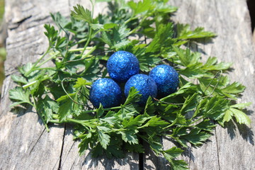 Blue shiny Easter eggs in green herbs nest