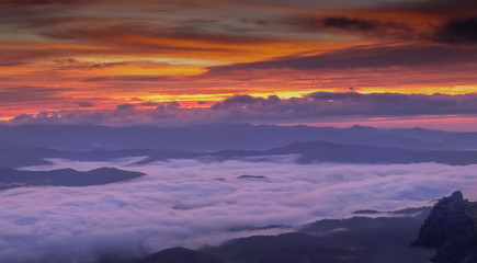 Mountain view morning of the hills around with sea of mist and colorful red sun light in the sky background, twilight at Doi Samur Dao, Sri Nan National Park, Nan, Thailand.